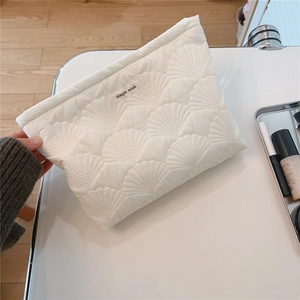 Detailed close-up of quilted white clutch featuring simple wish embroidery and soft shell texture