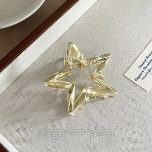 Detailed view of a 6cm golden star-shaped metal hair claw clip with a glossy finish