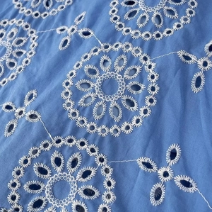 Detail of blue cotton fabric with white Broderie Anglaise eyelet floral embroidery