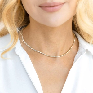 Close-up of a gold-plated tennis necklace with clear round zircons on model neck