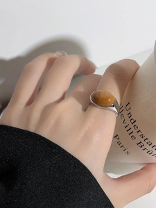 Macro detail of silver alloy ring featuring a tiger eye resin heart inlay on a finger