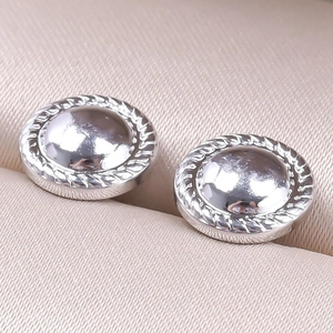 Macro detail of silver geometric stud earrings with polished dome and rope texture trim