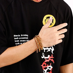 Close-up of three gold-plated stainless steel curb and link chains worn on a male wrist