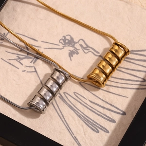 Detail of gold and silver spiral cylinder pendants on sleek snake chains in a frame