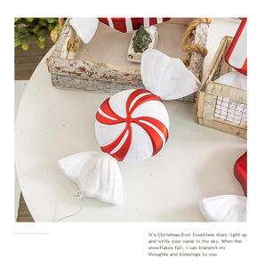 Close-up of red and white spiral candy Christmas ornaments with glitter details on table