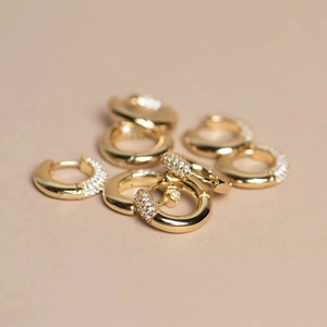 Classic gold-plated huggie hoop earrings with sparkling cubic zirconia on beige background