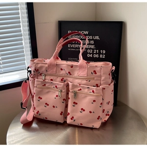 Close-up of pink tote bag with cherry print featuring front zipper pockets and straps