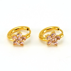 Macro detail of gold flower earrings featuring pink zircon petals and hoop closure