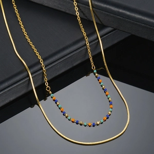 Close-up of double-layer gold stainless steel necklace with colorful beads on dark surface