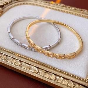 Detail of oval link bangles in gold and silver finish with micro-pave cubic zirconia