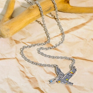 Detail of silver bird necklace with enamel colors and blue stone on a branch