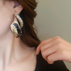 Close-up of a model wearing high-polish silver abstract curved earrings in a minimalist style