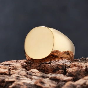 Macro detail of polished gold signet ring on textured tree bark background