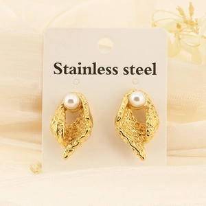 Détail de boucles d'oreilles géométriques dorées avec perles blanches sur carte