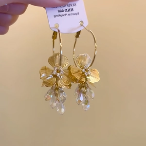 Detail of gold flower hoop earrings with zircon crystals and S925 silver needle on tag