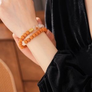Macro detail of double-layered Bodhi seed bracelet with white beads and gold metal charm