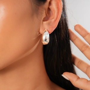 Close-up of polished silver teardrop earrings worn by a model for a stylish metal look