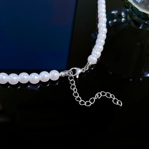 Detailed macro view of the silver lobster clasp and extension chain on white pearl necklace