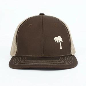 Close-up of the white palm tree embroidery on a brown and beige mesh trucker hat