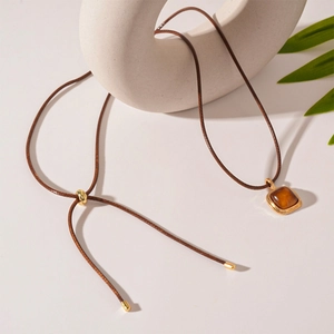 Detail of square amber resin pendant on adjustable brown cord necklace with gold accents