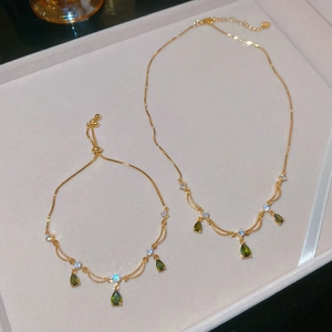 Dettaglio del set di gioielli dorati con pietre verdi a goccia in una scatola regalo