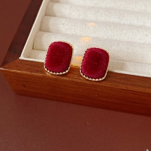 Macro view of rectangular burgundy velvet earrings with golden twisted rope metal frame