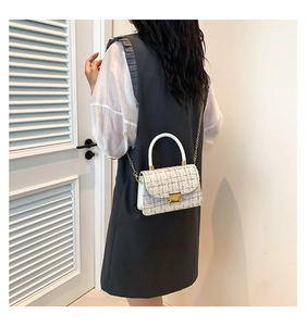 Gros plan du sac bandoulière en tweed élégant avec chaîne dorée porté par un mannequin
