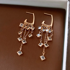 Macro detail of 18K gold-plated rhombus tassel earrings with sparkling crystals