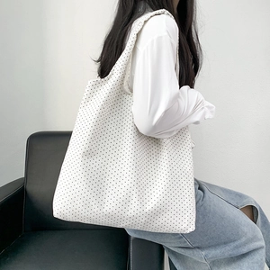 Minimalist polka dot canvas tote bag shown on a model for daily casual shoulder use