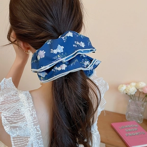 Detailed back view of a dark blue floral scrunchie with lace edges on a ponytail
