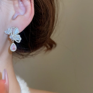 Detail of model wearing butterfly drop earrings with pink zircons and silver needles