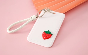 Detail of white cartoon card holder with red strawberry decor and white braided wrist strap