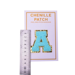Detailed view of light blue chenille letter A patch with gold sequins and adhesive backing