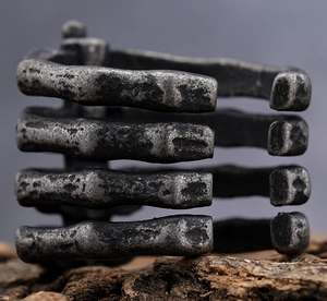 Macro view of industrial bone-style cuff bracelet with antique silver finish on wood bark