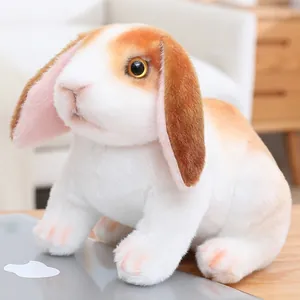 Gros plan d'une peluche de lapin à oreilles tombantes réaliste posée sur un bureau