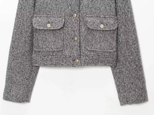 Détail de la veste en tweed gris montrant la texture du tissu et les boutons dorés gaufrés