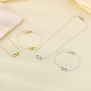Macro view of gold and silver snake chains with infinity pendants on marble