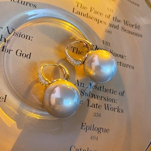 Macro detail of French style grey pearl earrings with gold zircon hoops on glass
