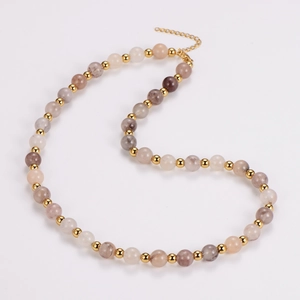 Detail of beaded necklace featuring earth-toned agate stones and golden metal accents