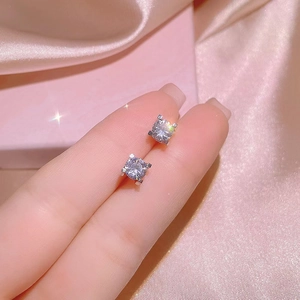 Classic silver zirconia stud earrings with four-claw setting on pink satin background