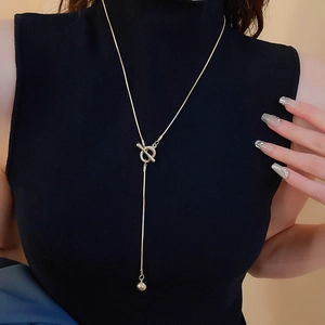 Detail of gold OT buckle necklace on a black turtleneck showing the elegant Y-shape design