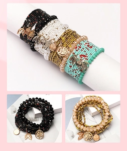 Close-up of bohemian multilayer bead bracelets with tree of life and leaf pendants