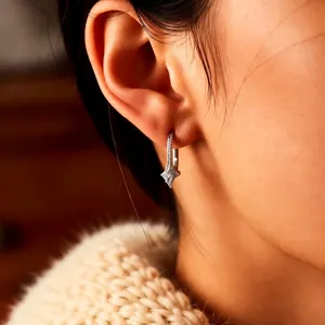 Silver star drop earrings with zircons worn by a model in a cozy knit sweater