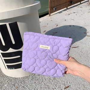 Detail of purple quilted heart pattern pouch with Sonkka woven label in natural light
