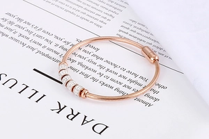 Détail d'un bracelet maille serpent en or rose avec cinq breloques pavées de diamants sur magazine