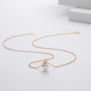 Close-up of small pearl pendant necklace with gold chain and tiny diamond accents