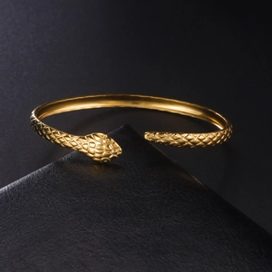 Macro view of gold snake bracelet showing detailed scale texture and metallic finish