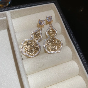 Detailed close-up of golden gourd earrings with hollow rose patterns and zircon inlay