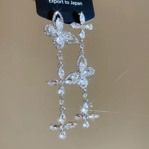 Macro shot of silver butterfly tassel earrings with sparkling crystals and cross pendant