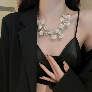 Detailed view of a silver leaf statement necklace with intricate vein textures on model